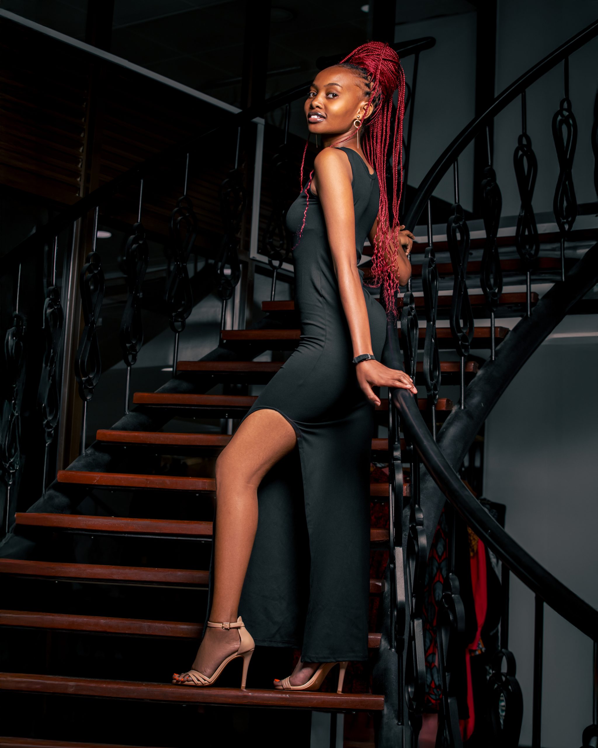 Edgy high-fashion portrait of a lady with red braids on a spiral staircase in Nairobi CBD, by MintGlint Studios