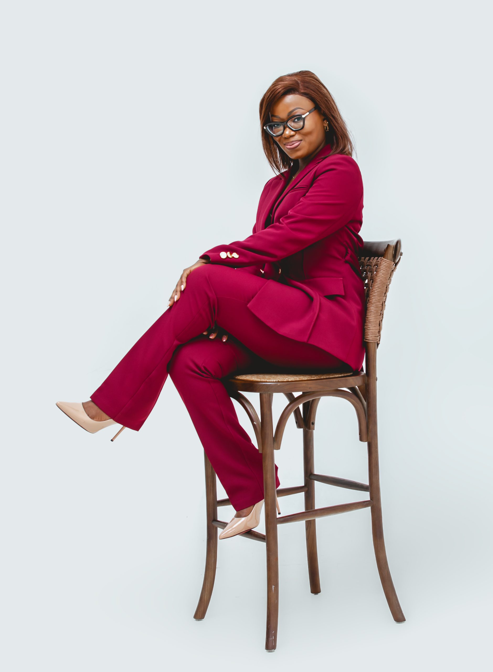 Woman in a maroon business suit sitting on a high stool at MintGlint Studios, the best photography studio in Nairobi CBD.